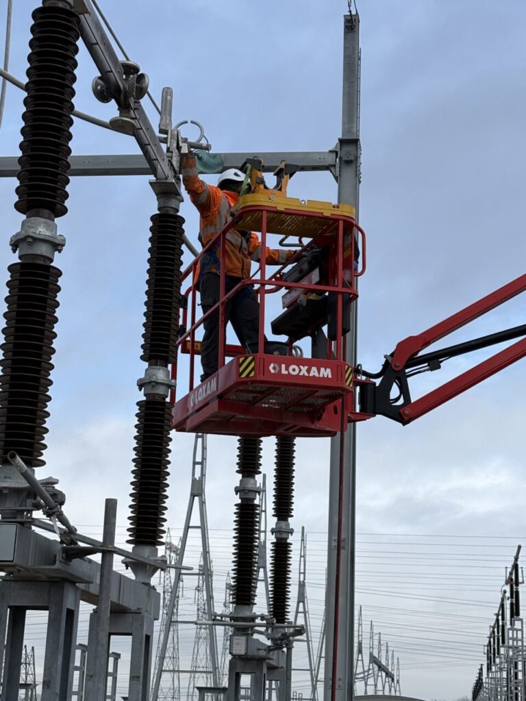 Operator using the Haulotte Heavy Tool Tray to securely hold a crimping tool in an aerial work platform.